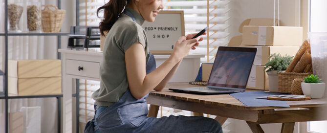 woman sat tapping on phone at desk
